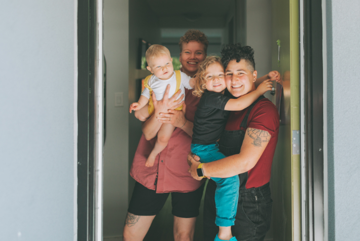 A smiling, LGBTQ+ family in their home